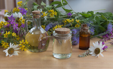 Essential oils,with herbs and flowers in the background.