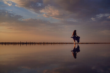 Elegant woman in silky dress walking by a salt lake.
