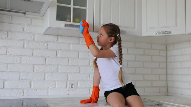 Little girl wipes cloth kitchen. Chores for children.