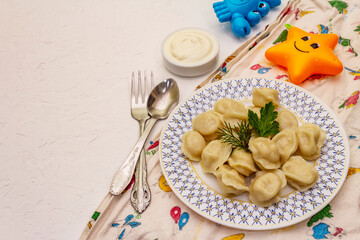 Hot meat dumplings with fresh sour cream. Homemade healthy kid's food, funny toys