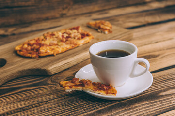 Little pizza on a wooden table with a cup of coffee. Fast food cooked at home.