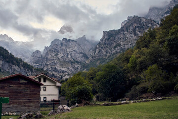 Fototapeta na wymiar Little Houses in front of mountains whit dramatic clouds.