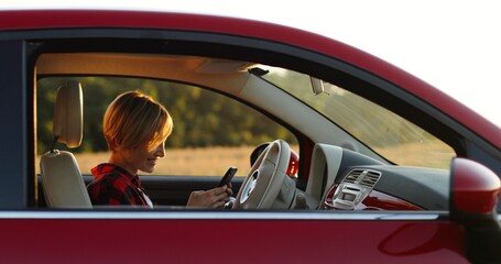 Portrait of beautiful hipster woman in car. Girl using smartphone sitting in car.