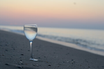 wine glass stands on the beach near the sea