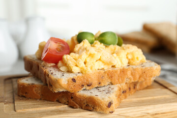 Tasty scrambled egg sandwich on wooden board, closeup