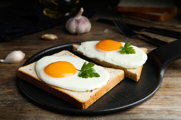 Tasty fried eggs with bread and parsley on slate board