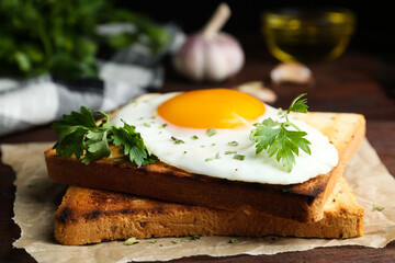 Tasty fried egg with toasts and parsley on wooden table, closeup