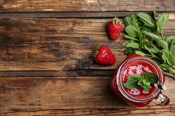 Tasty strawberry smoothie with mint in mason jar on wooden table, flat lay. Space for text