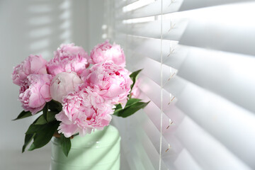 Bouquet of beautiful peonies near window, closeup. Space for text