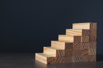Steps made with wooden blocks on dark background, space for text. Career ladder