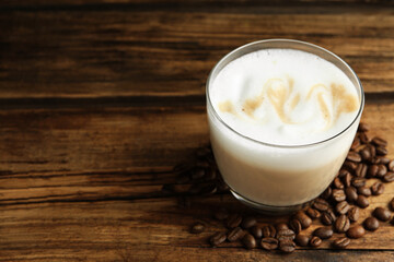 Delicious latte macchiato and coffee beans on wooden table, space for text