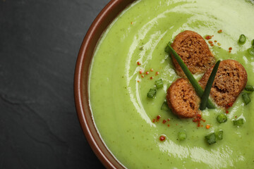 Tasty homemade zucchini cream soup on black table, top view