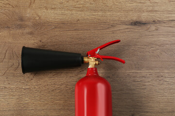 Naklejka premium Fire extinguisher on wooden background, top view