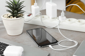 Smartphone charging with cable on light stone table