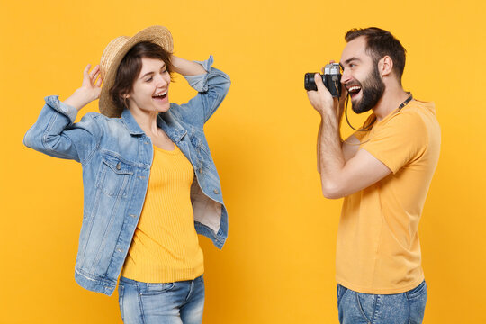 Funny tourists couple friends guy girl in summer clothes hat isolated on yellow background. Passenger traveling abroad on weekends. Air flight journey. Taking pictures with retro vintage photo camera.