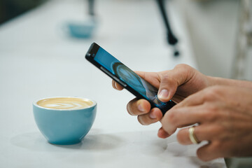 chico joven bebiendo cafe con mascara puesta por coronavirus en cafeteria moderna haciendo foto a...