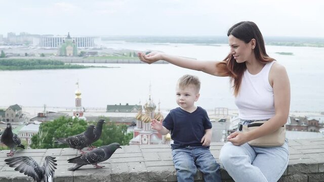 Mom with her son feeds pigeons