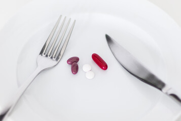 Medicine pills and capsules on a plate as a meal from a person's perspective. Healthcare and diet.