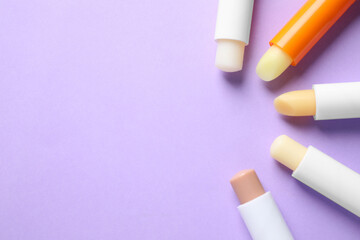 Hygienic lipsticks on lilac background, flat lay. Space for text