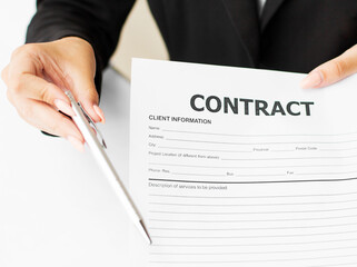 Woman wearing a suit sitting in a table showing a contract and where the signer must sign