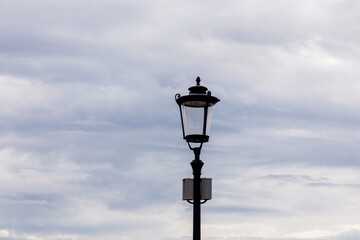 Fototapeta na wymiar Modern vintage-style LED street lamp against a cloudy sky