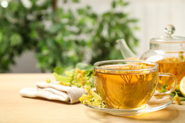 Cup of tea with linden blossom on wooden table. Space for text