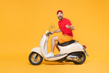 Fototapeta na wymiar Delivery man in red cap t-shirt uniform driving moped motorbike scooter isolated on yellow background studio Guy employee working courier Service quarantine pandemic coronavirus virus covid-19 concept