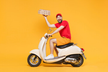 Delivery man in red cap t-shirt uniform driving moped motorbike scooter hold pizza in cardboard flatbox isolated on yellow background studio Fun guy employee working courier Service quarantine concept