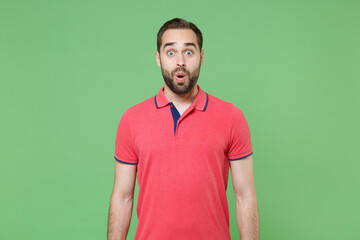 Shocked young bearded man guy in casual red pink t-shirt posing isolated on green wall background...