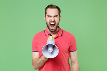 Crazy young bearded man guy in casual red pink t-shirt posing isolated on green background studio portrait. People sincere emotions lifestyle concept. Mock up copy space. Screaming in megaphone.