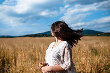 Portrait of a girl in a wheat field. Portrait of a beautiful girl in a white dress and hat on a wheat field. Girl in a white dress and hat. Wheat field. Portrait of a young woman in nature.