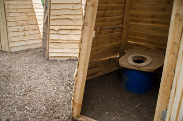 Wooden ecological composting toilet on countryside with sawdust