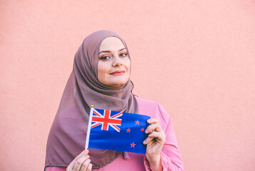 Muslim woman in a scarf  holds flag of New Zealand