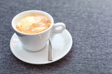 Affogato coffee with ice cream in a ceramic cup on a textile chair