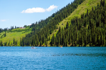 Beautiful view to Kolsai or Saty lake with mountains background. Summer vacation concept. Scenic travel background. Travel in Kazakhstan concept.