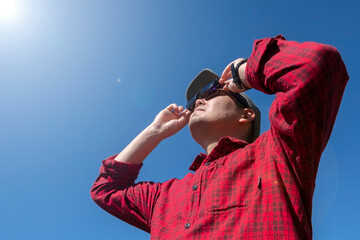 Man is looking on solar eclipse through three sunglasses. Sun eclipse concept.
