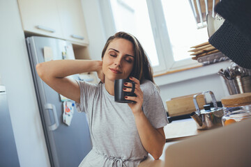 Fototapeta na wymiar young woman drinking morning coffee in her kitchen