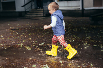 little boy outdoors playing in the rain.