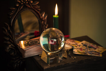Magic crystal ball fortune teller ,love telling,  esoteric concept, mystical scene with candles, tarot cards on a table