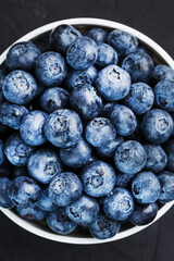 Blueberries in a white Cup on a black textured background.