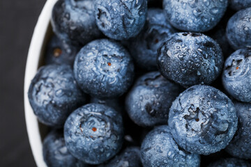 Organic blueberries in a white Cup on a black Board.