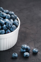 Blueberries in a white Cup on a black textured background.