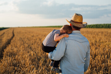 Naklejka na ściany i meble farmer and his grandson walking fields of wheat