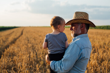 farmer and his grandson walking fields of wheat