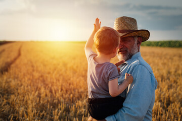 farmer and his grandson walking fields of wheat