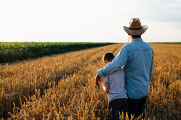 Naklejka na ściany i meble farmer and his son walking fields of wheat