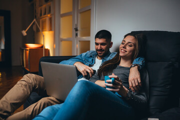 couple using laptop relaxing on sofa at home