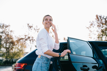 Happy female talking on phone leaving car