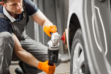 Car detailing. Man works with orbital polisher and polishing white automobile, close-up.