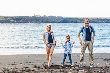 Happy family standing on the beach on the dawn time